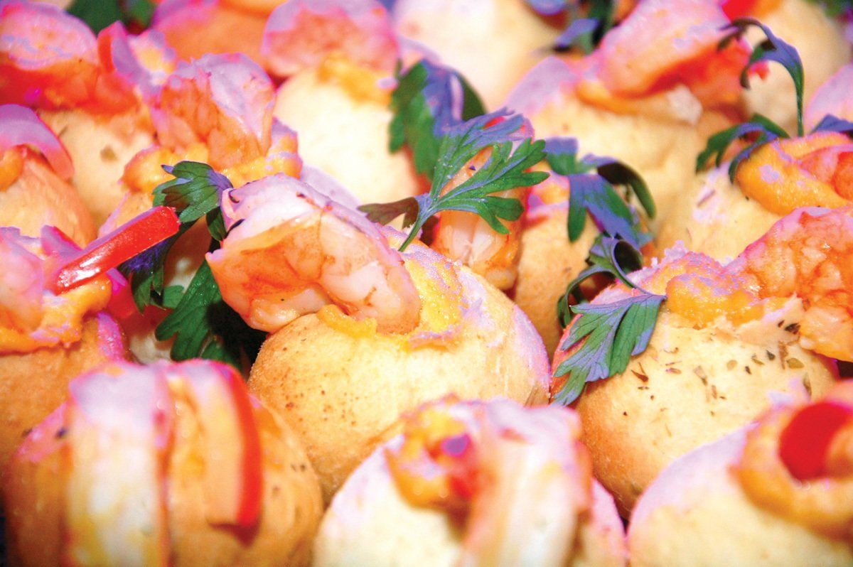 Canapés assados coloridos, cobertos com ervas e fatias de pimentão vermelho.