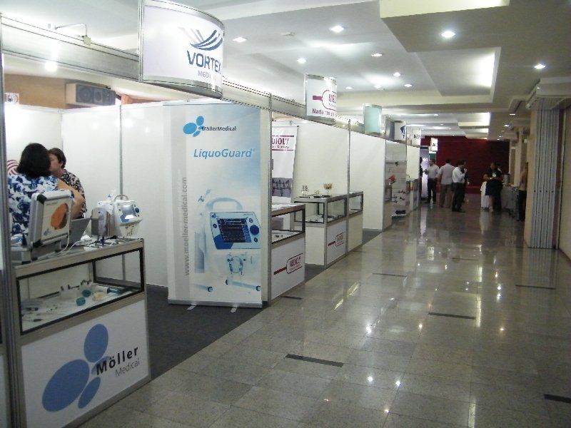 Corredor interno de feira comercial com estandes de exposição e algumas pessoas caminhando.
