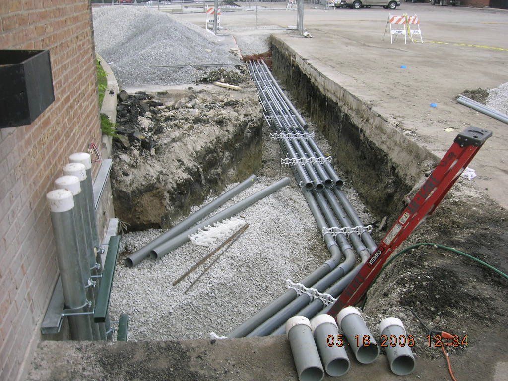 A bunch of pipes are laying in the dirt next to a ladder