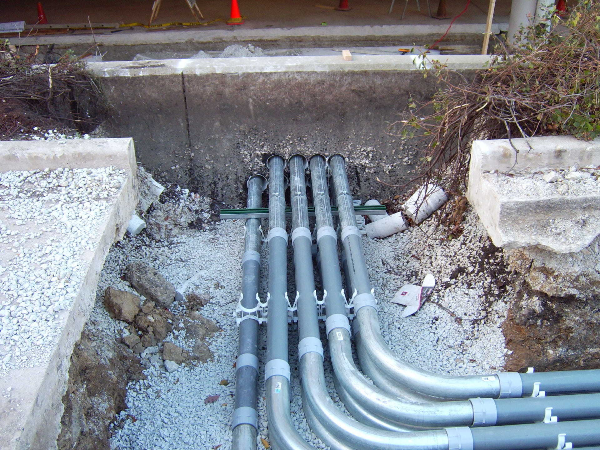 A bunch of metal pipes are laying in the dirt