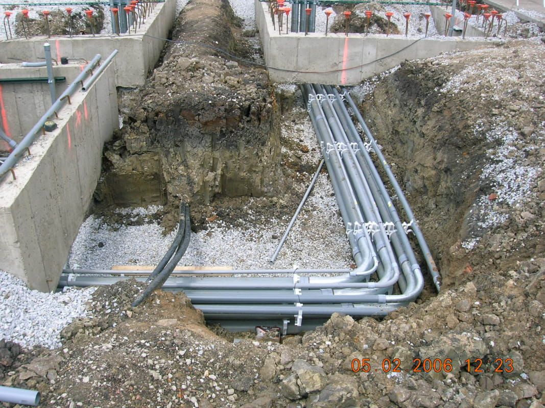 A bunch of pipes are laying in the dirt