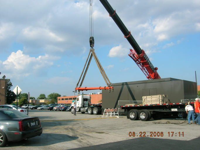 A truck is being lifted by a crane in a parking lot