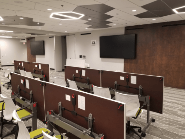 A conference room with tables and chairs and a flat screen tv