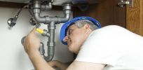 A plumber fixing a drain under a sink