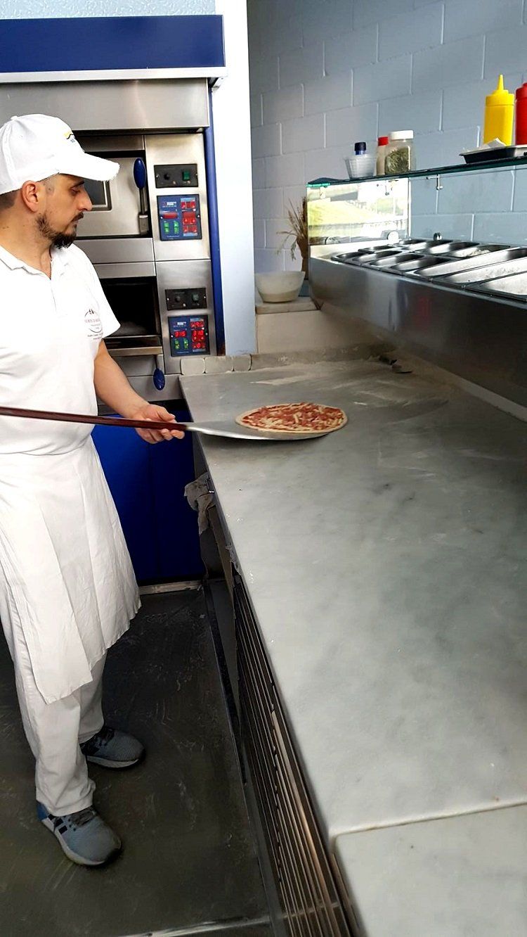 Pizzaiolo inforna la pizza con pala