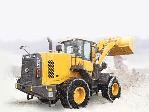 Yellow front loader moving snow in a snowy landscape