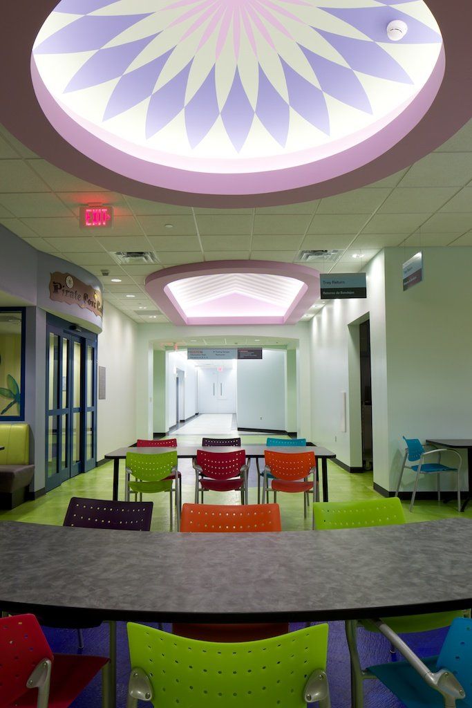 A brightly lit hallway with colorful chairs and tables. A domed ceiling with a purple and pink design.