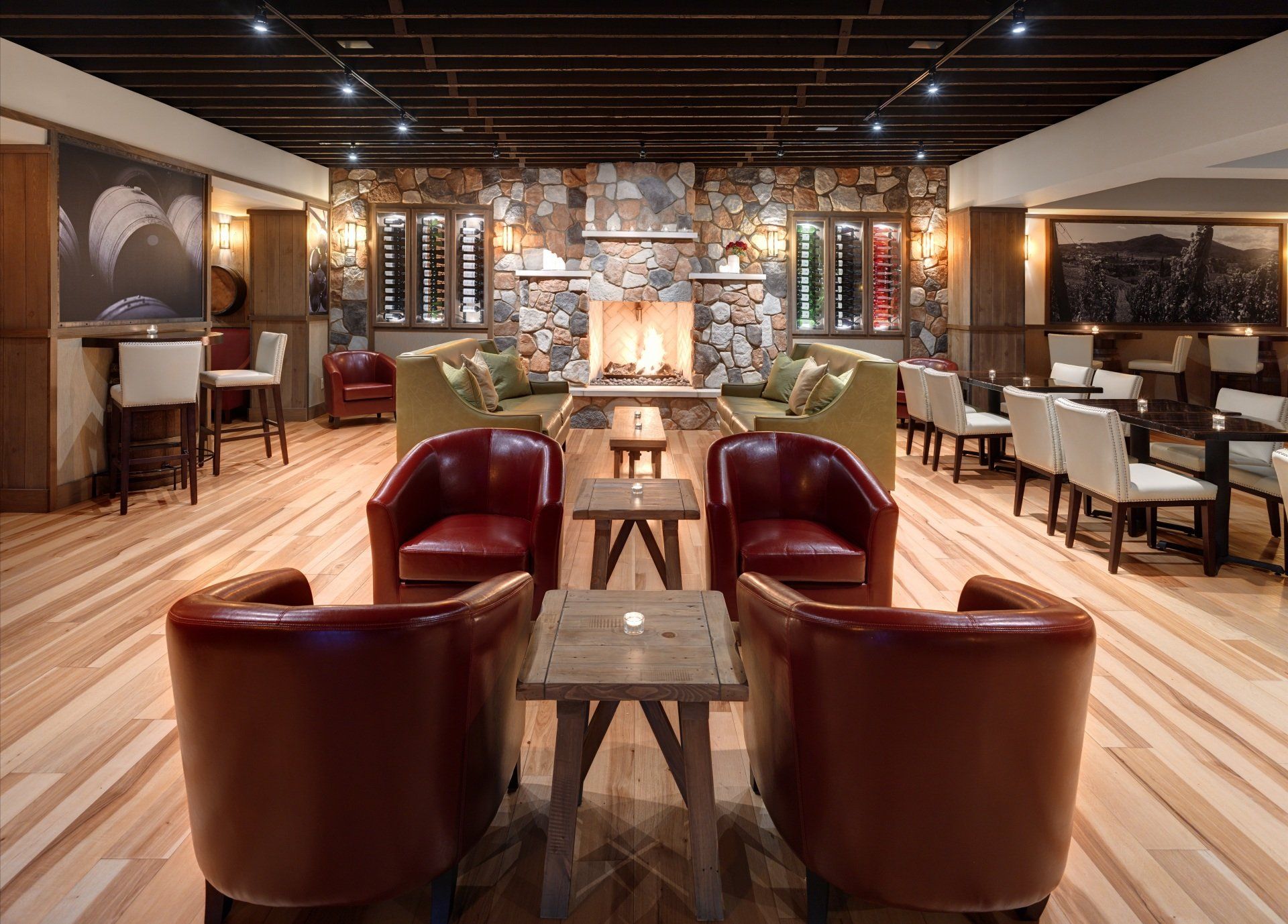 Cozy lounge with a stone fireplace, leather armchairs, and a long wooden bar with seating.