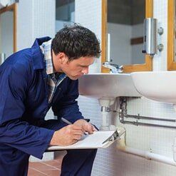 plumber looking at sink  — Kitchen Remodel in Tallahassee, FL