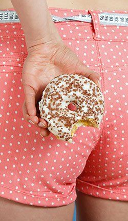 Une femme tient un beignet dont elle a croqué une bouchée.