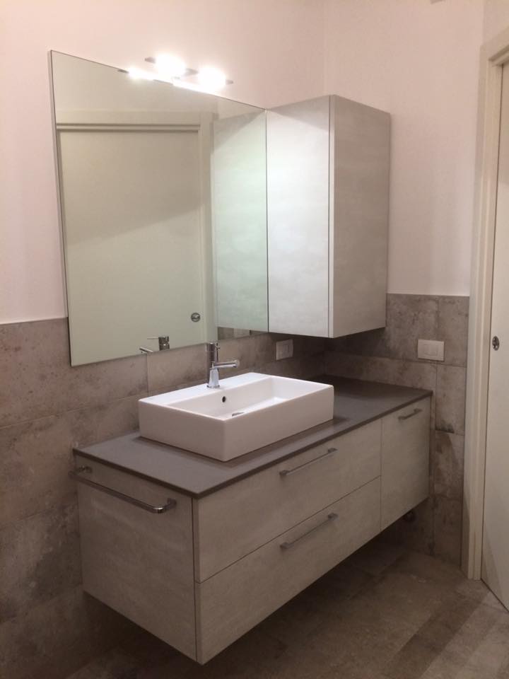 Mobile bagno moderno con lavabo rettangolare, mobiletto con specchio e piastrelle grigie a parete.