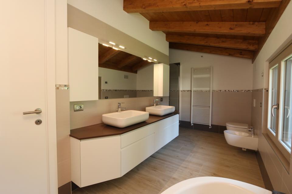 Bagno moderno con doppio lavabo, soffitto in legno, doccia e WC.