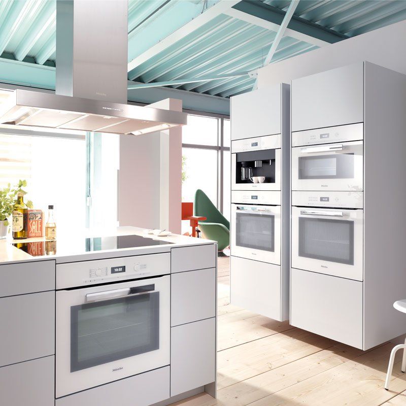 Cucina moderna bianca con elettrodomestici in acciaio inox integrati e soffitto verde menta.