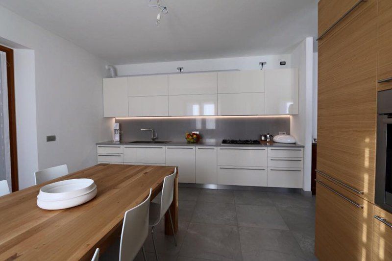 cucina con mobili bianchi e tavolo in legno