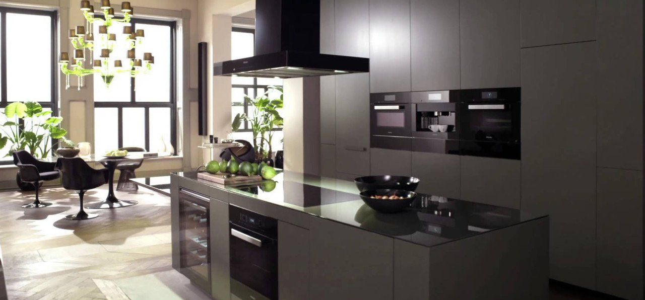 Cucina moderna con mobili scuri, isola e zona pranzo luminosa vicino a una finestra