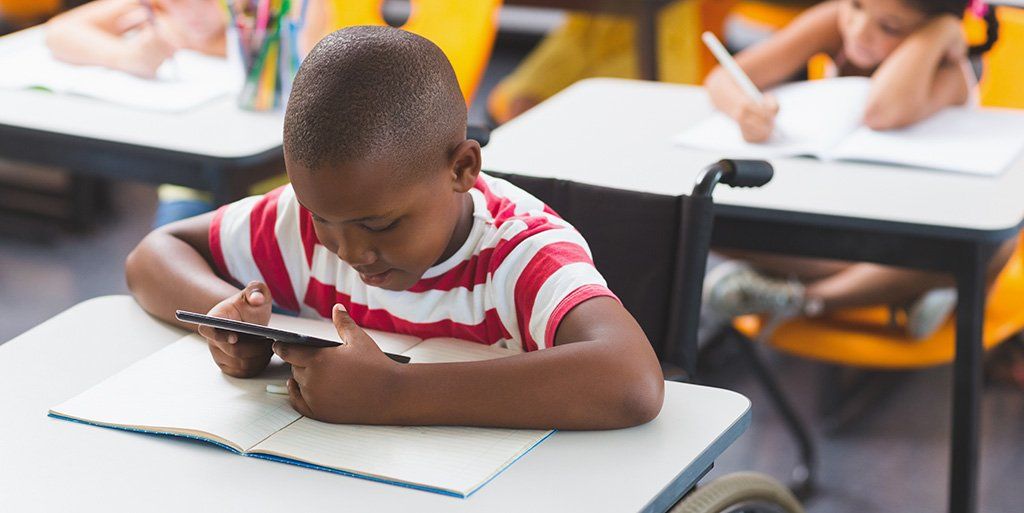 student with braille book and a mobile device
