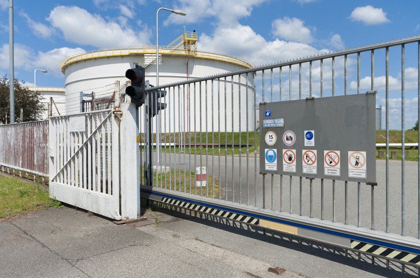 There is a sliding gate in front of a large tank.