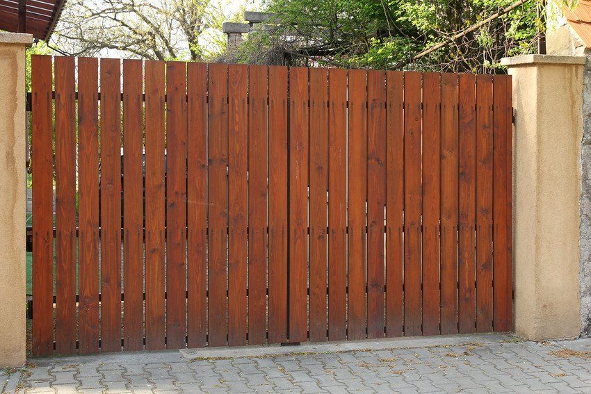 A wooden gate with a brick wall behind it
