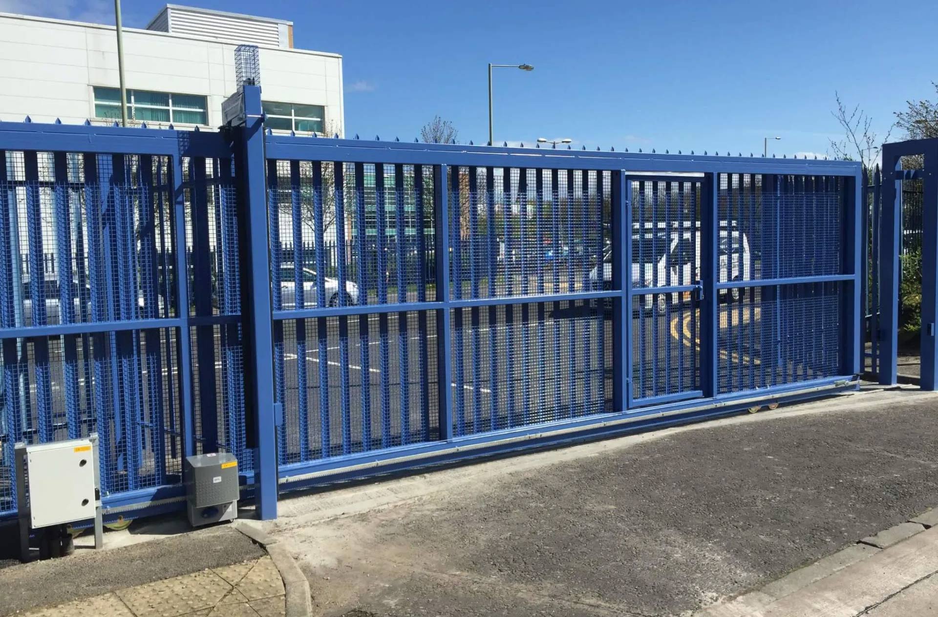 A blue sliding gate is open in front of a building.