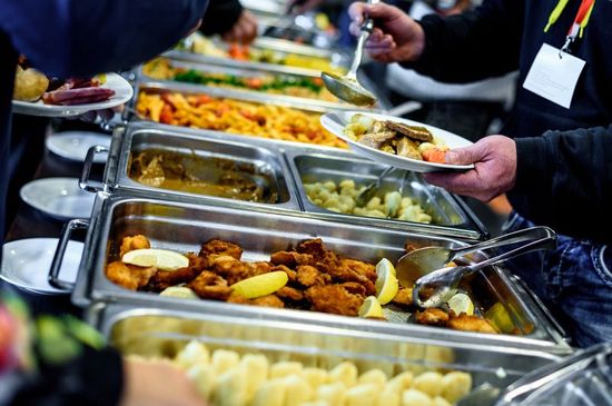 recipienti in metallo in un buffet con del cibo e delle persone che si servono