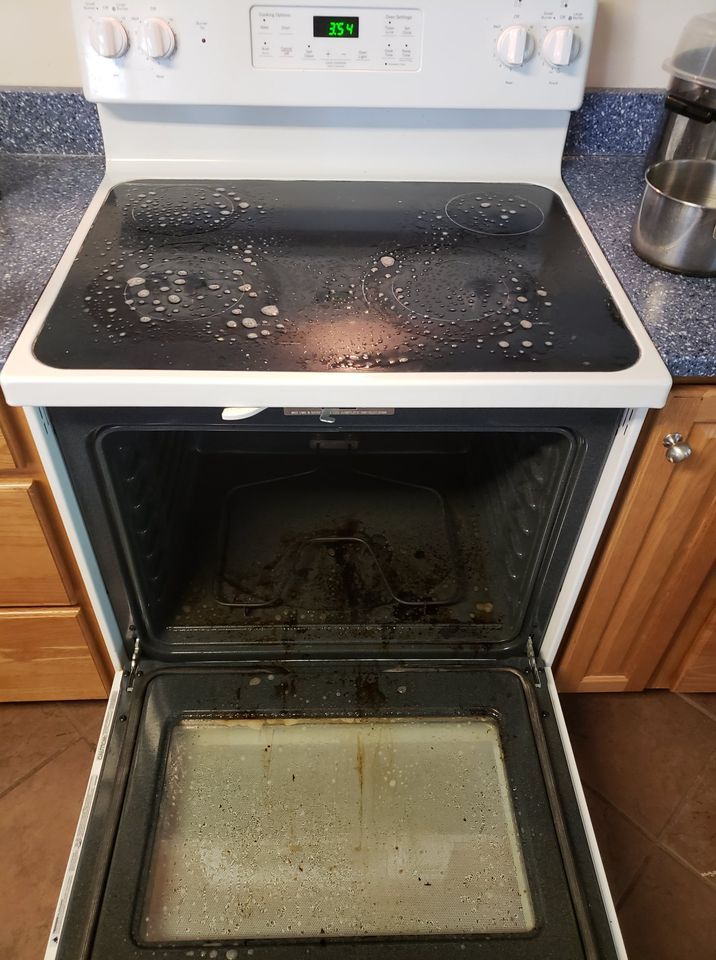 Dirty electric stovetop with oven door open, showing splatters and grime.