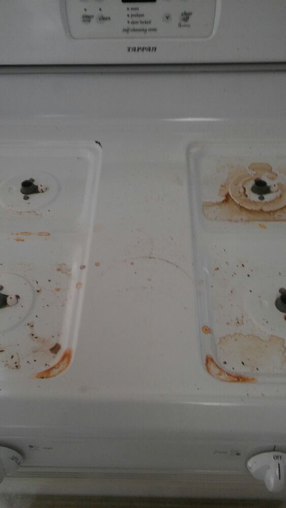 White electric stovetop with food residue around the burners and on the surface.