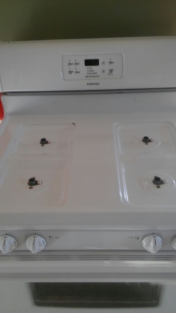 White electric stove with four burners, digital clock, and control knobs.