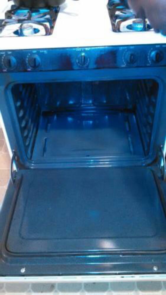 Open oven, showing interior racks and bottom, white oven exterior.