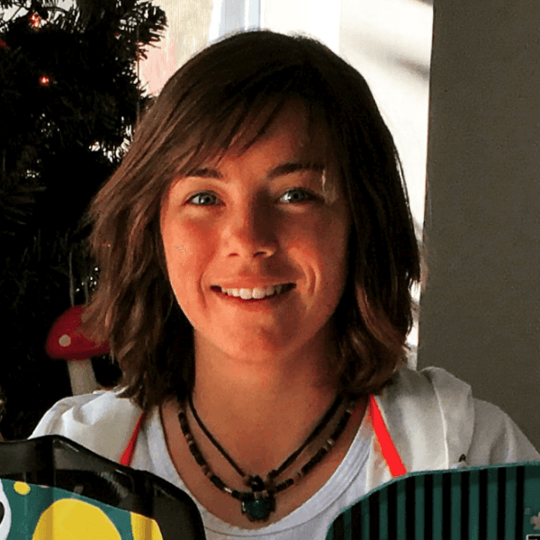 A woman wearing a necklace is smiling and holding a bag
