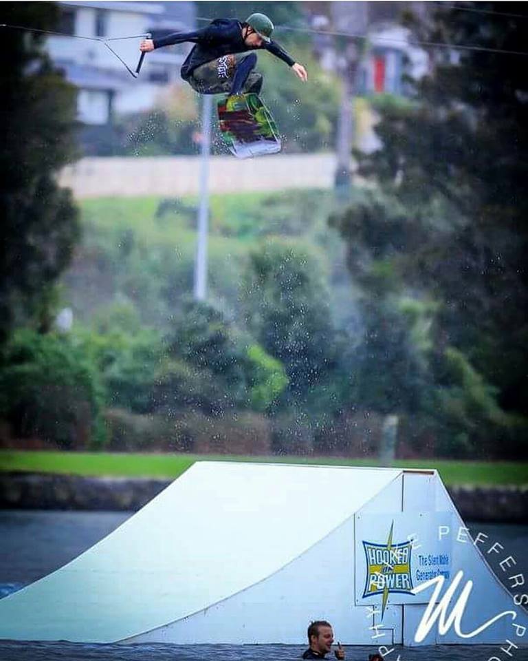 A man is jumping over a ramp in the water while riding a wakeboard.