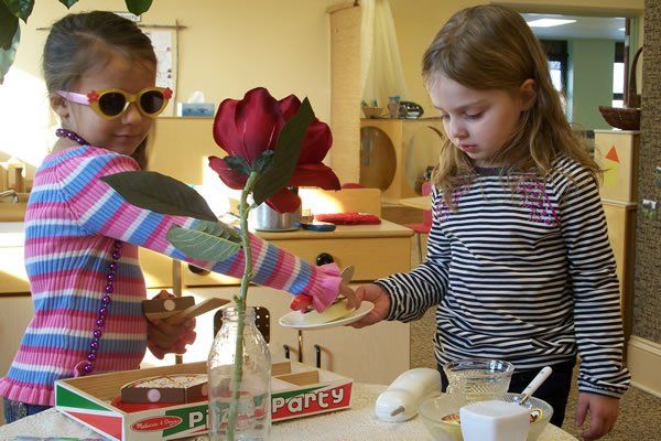 Two little girls are playing with a box that says party on it