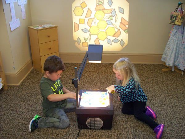 A boy and a girl are playing with a light box in a room.