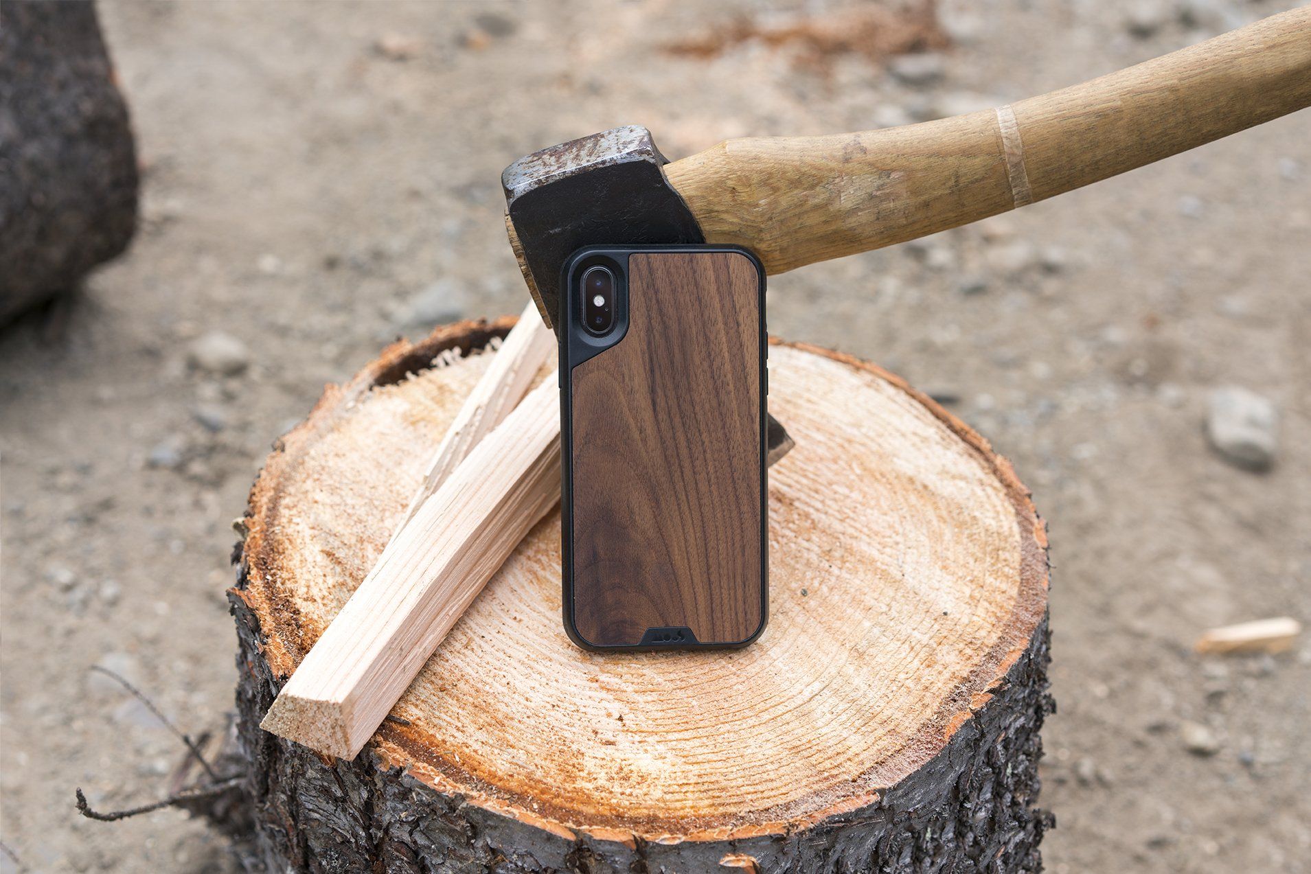 A phone in a wooden case is sitting on top of a tree stump.