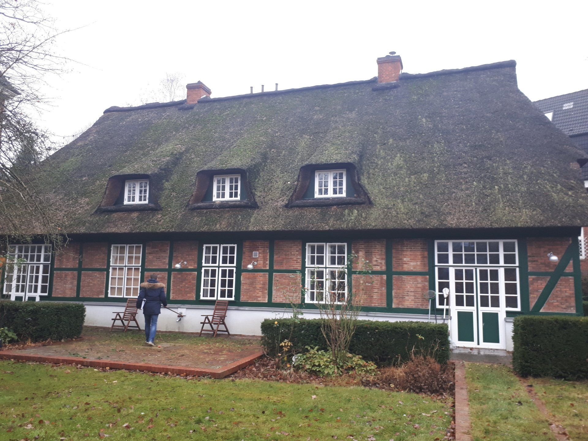 Ein Mann geht vor einem strohgedeckten Haus