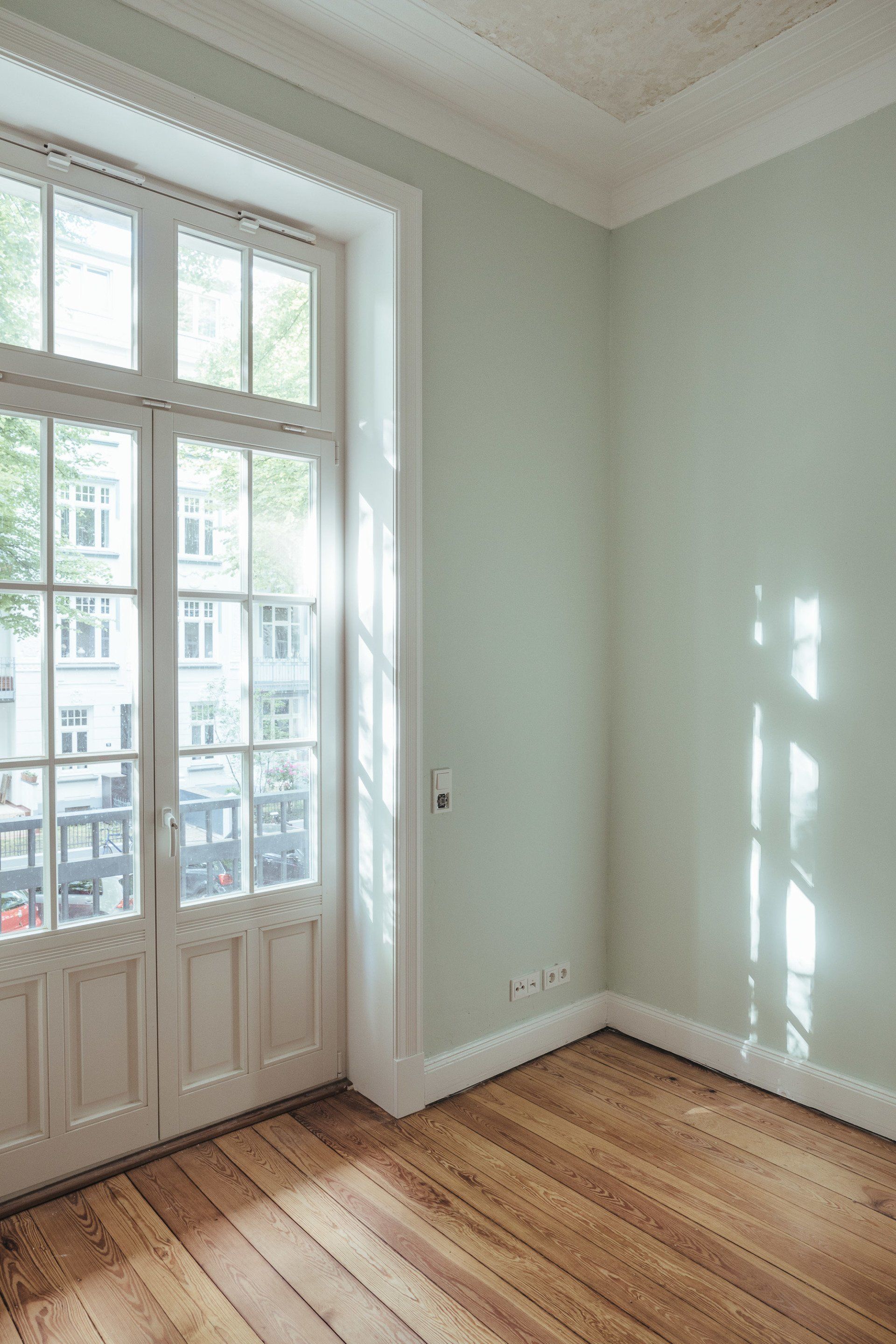 Ein leerer Raum mit Holzboden und einem großen Fenster.