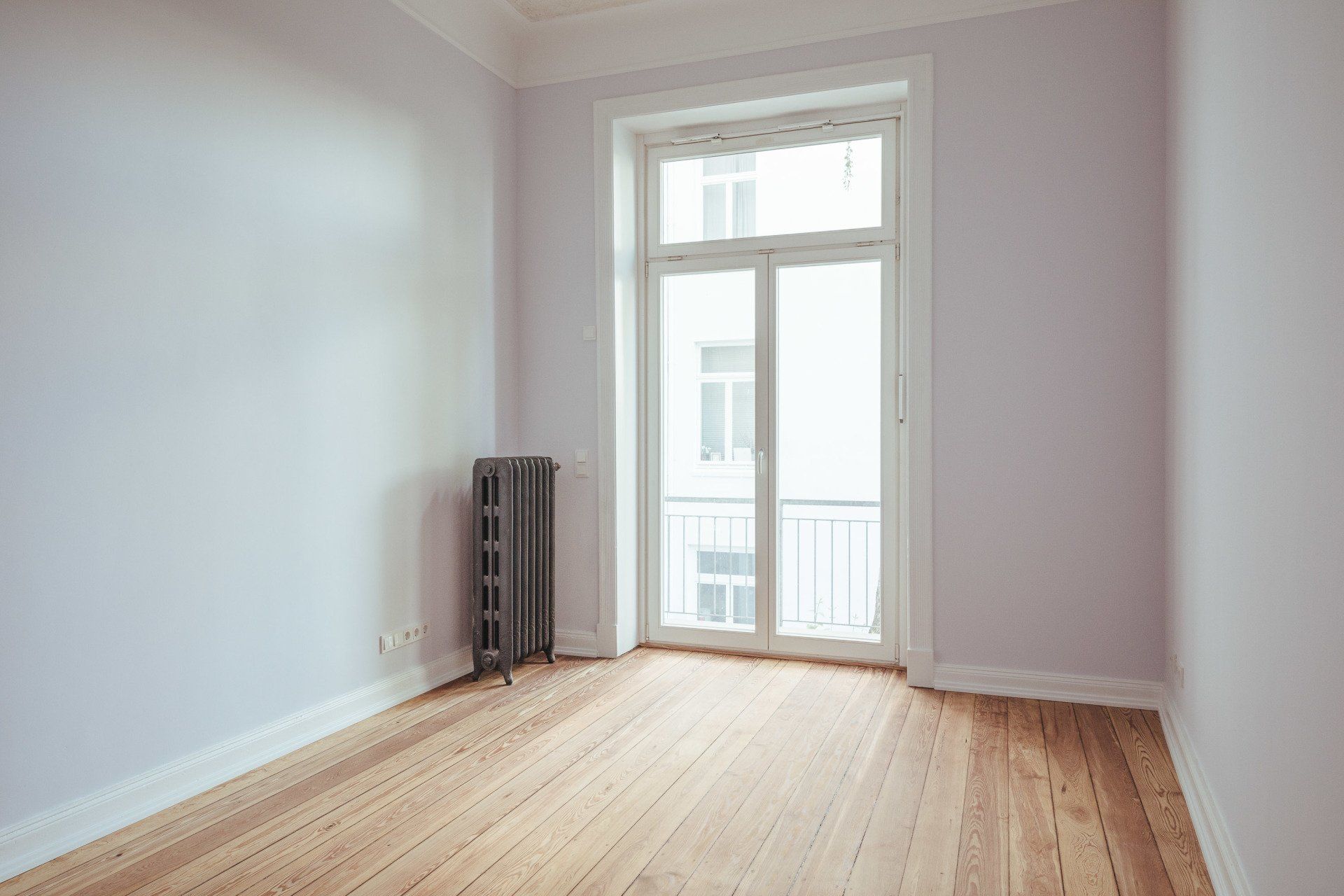 Ein leerer Raum mit Hartholzböden und einem großen Fenster.