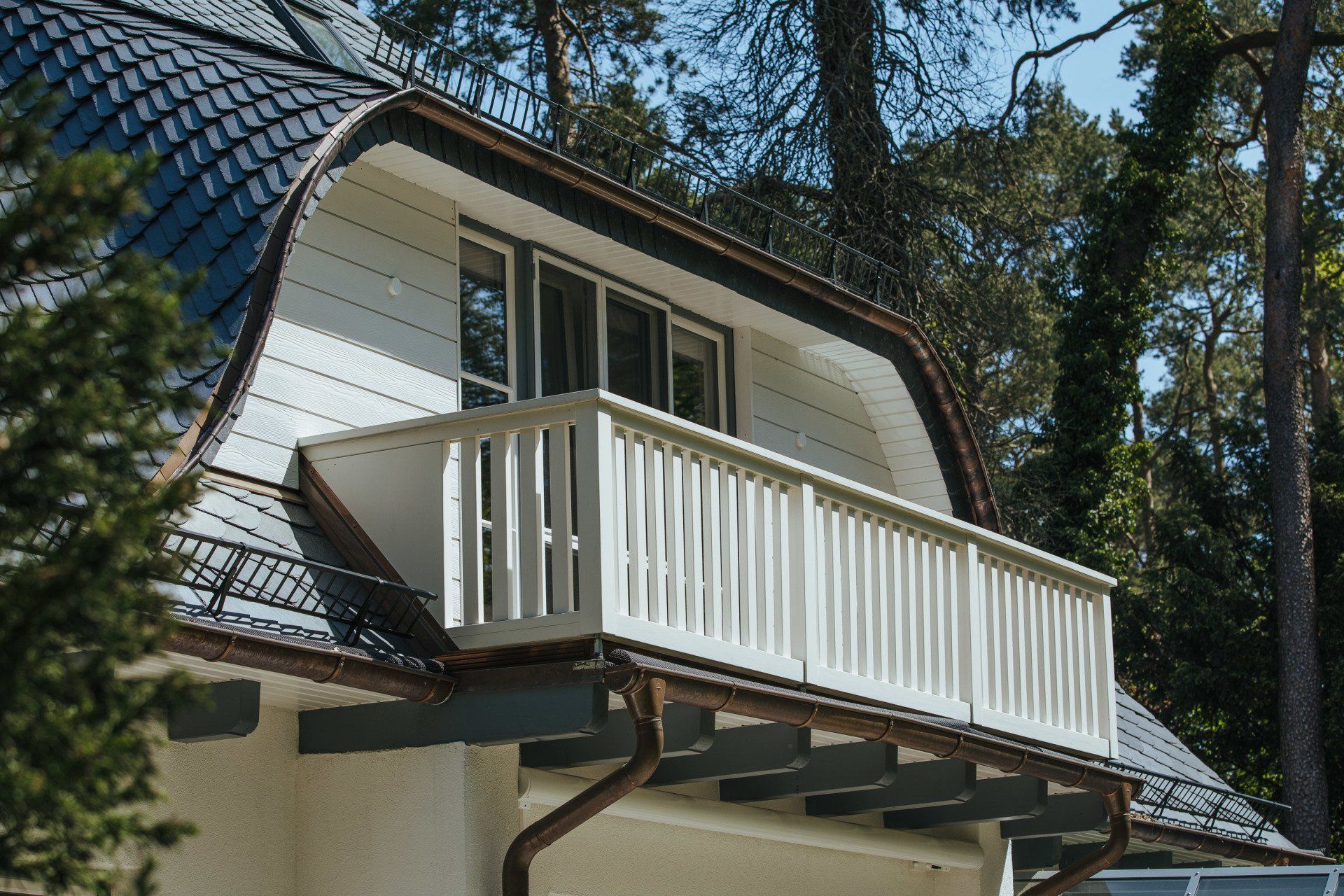 Ein Haus mit einem Balkon auf dem Dach, umgeben von Bäumen.