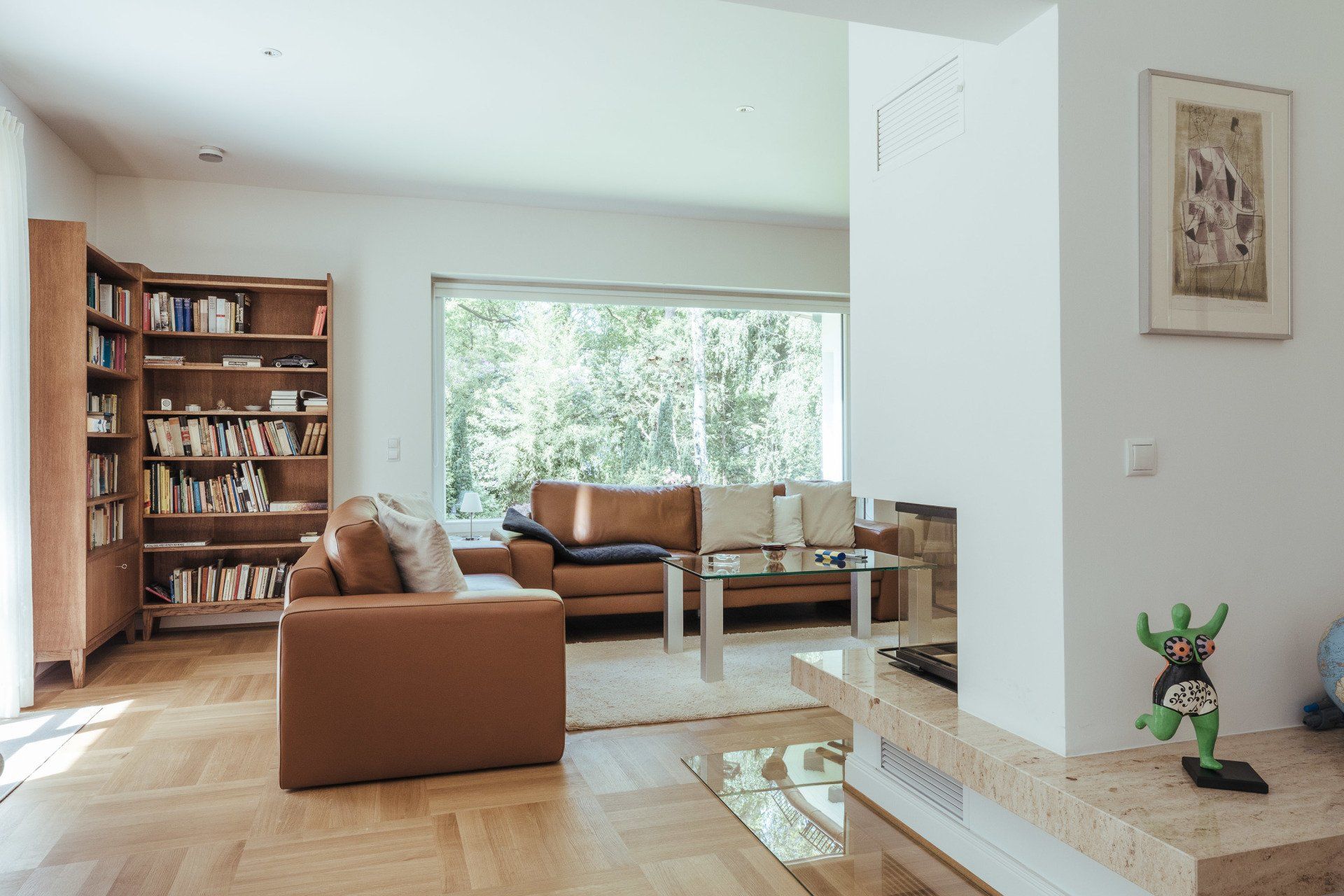 Ein Wohnzimmer mit Couch, Sessel, Couchtisch und Bücherregal.