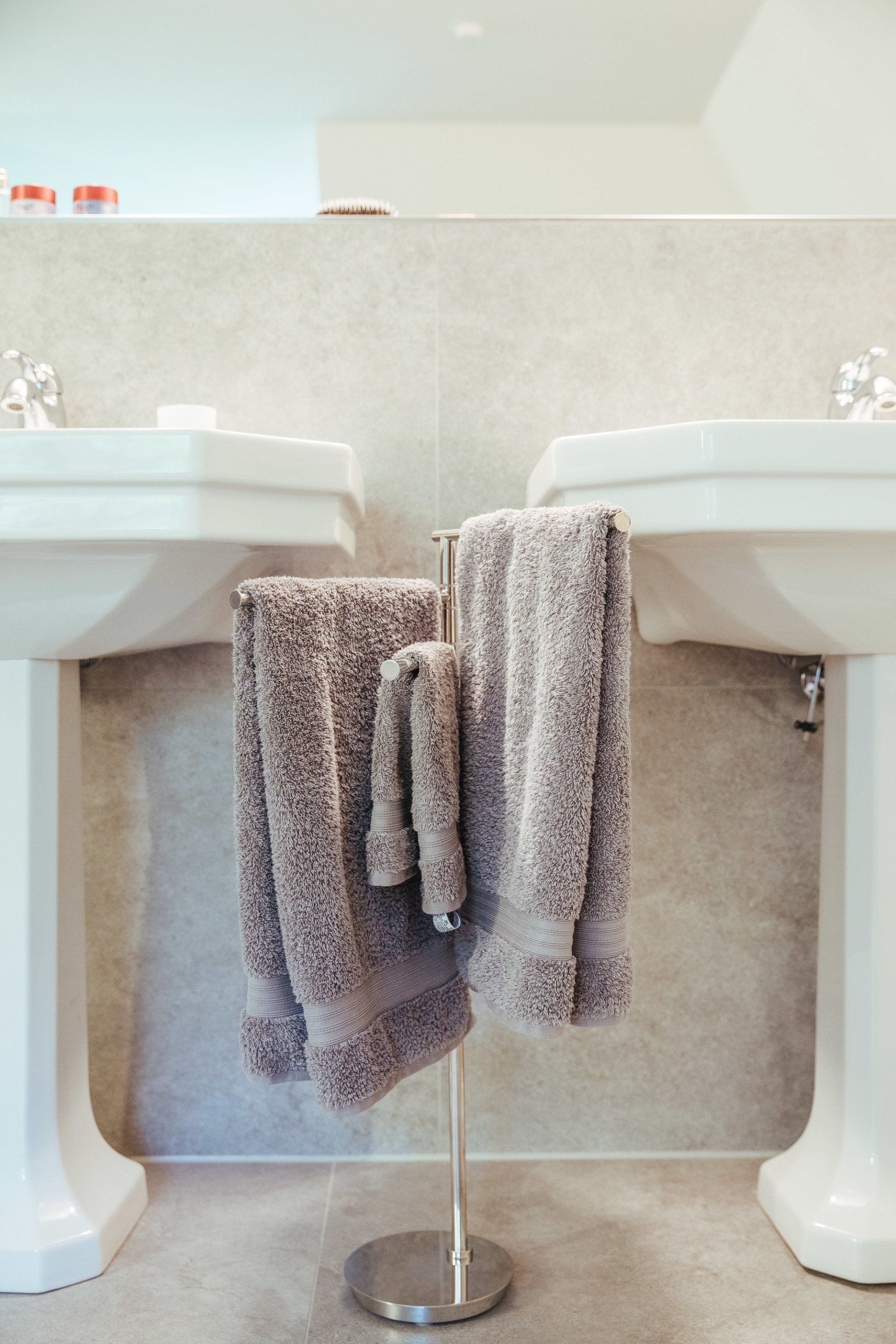Zwei Waschbecken in einem Badezimmer mit Handtüchern, die an einem Handtuchhalter hängen.