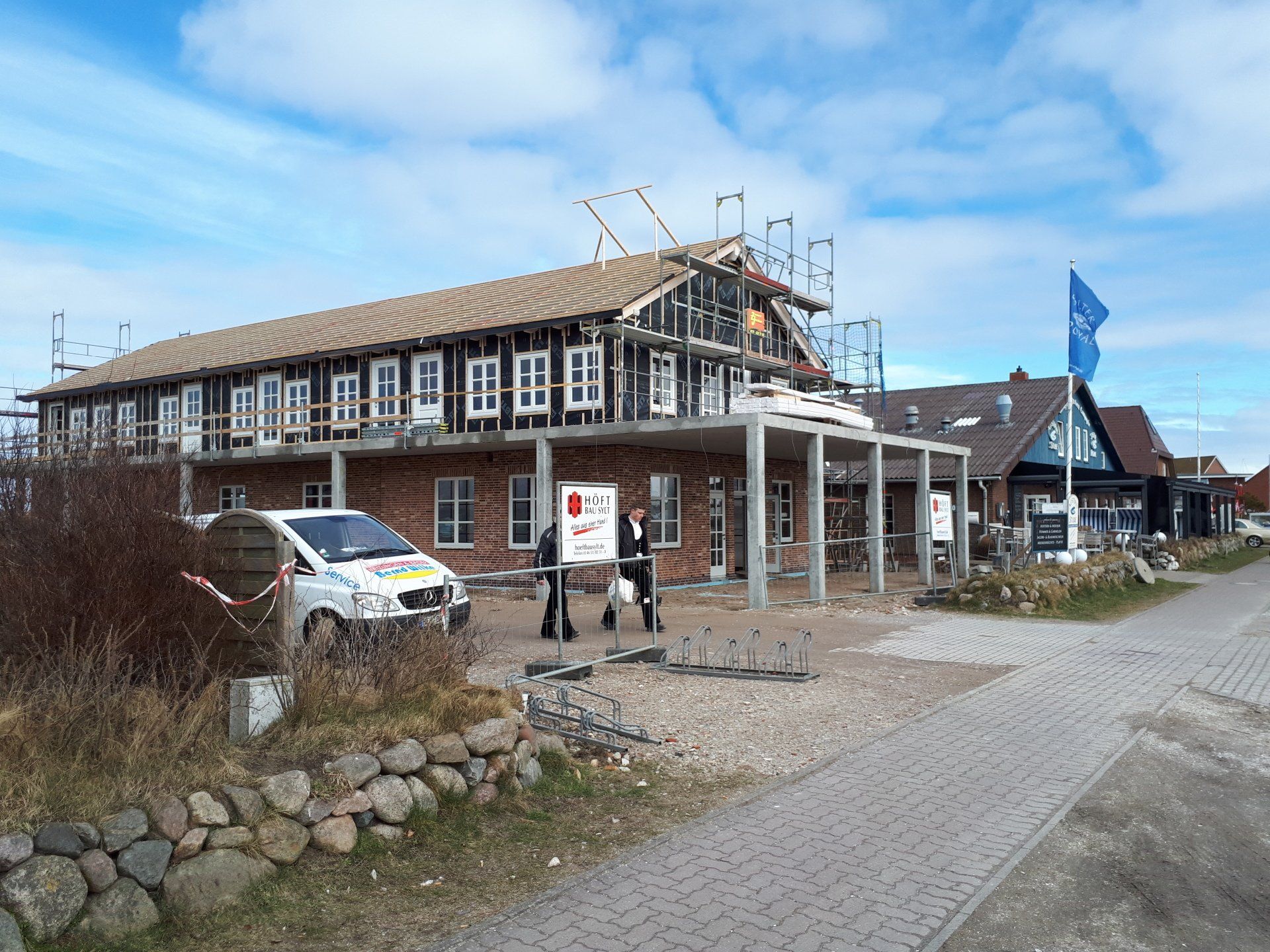 Eine Gruppe von Menschen steht vor einem im Bau befindlichen Gebäude.