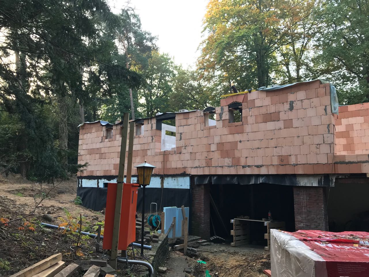 Mitten in einem Wald wird ein Backsteingebäude errichtet.