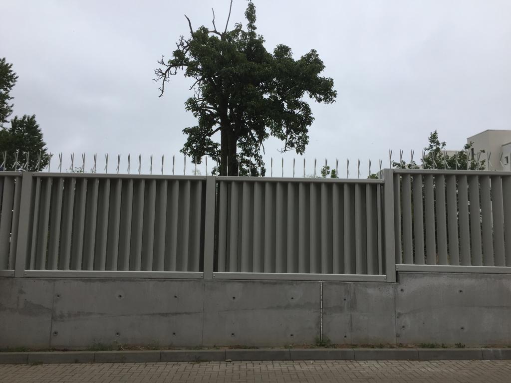 Ein Zaun mit einem Baum im Hintergrund an einem bewölkten Tag