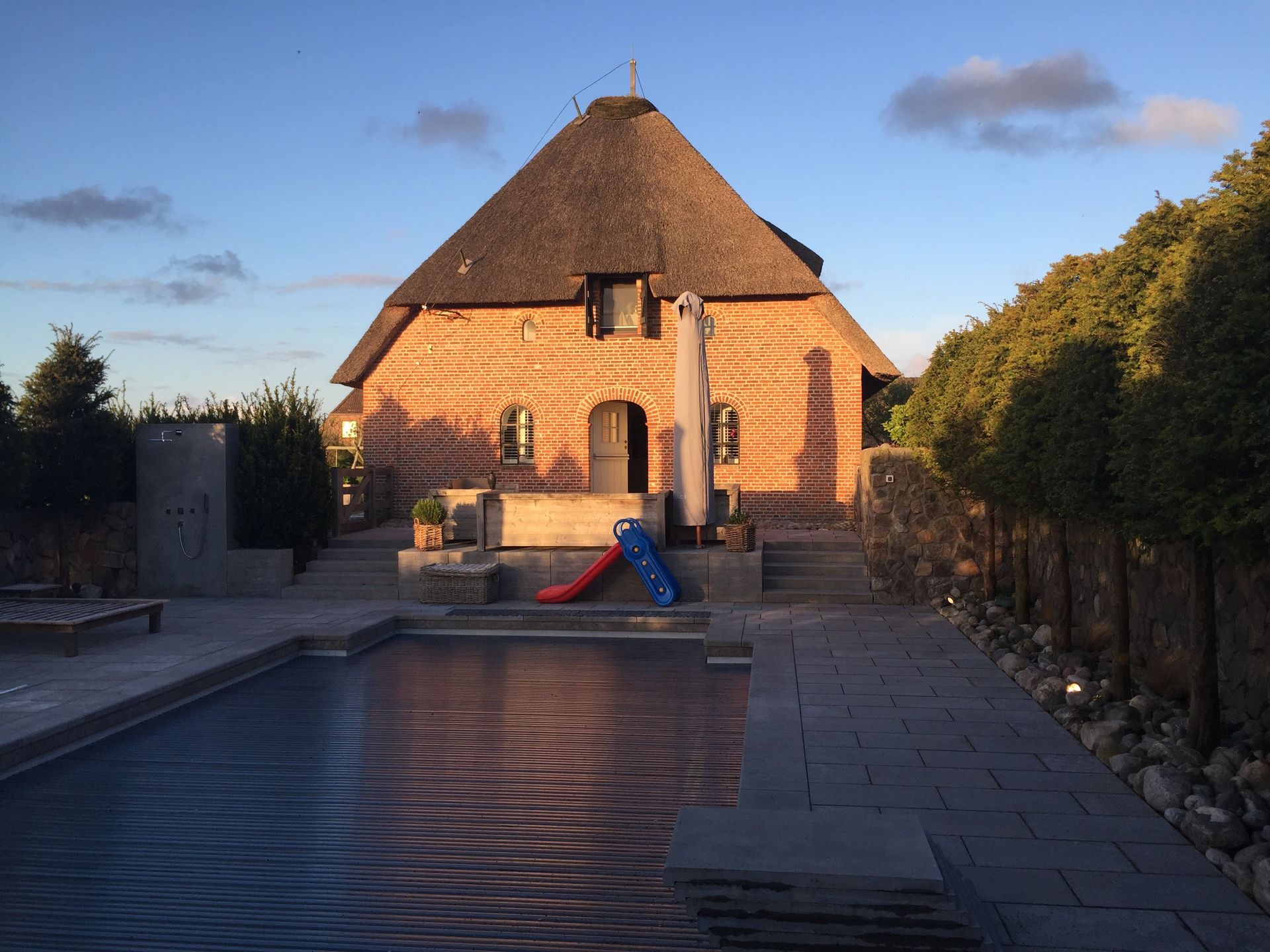Ein Haus mit Strohdach und einem Pool davor