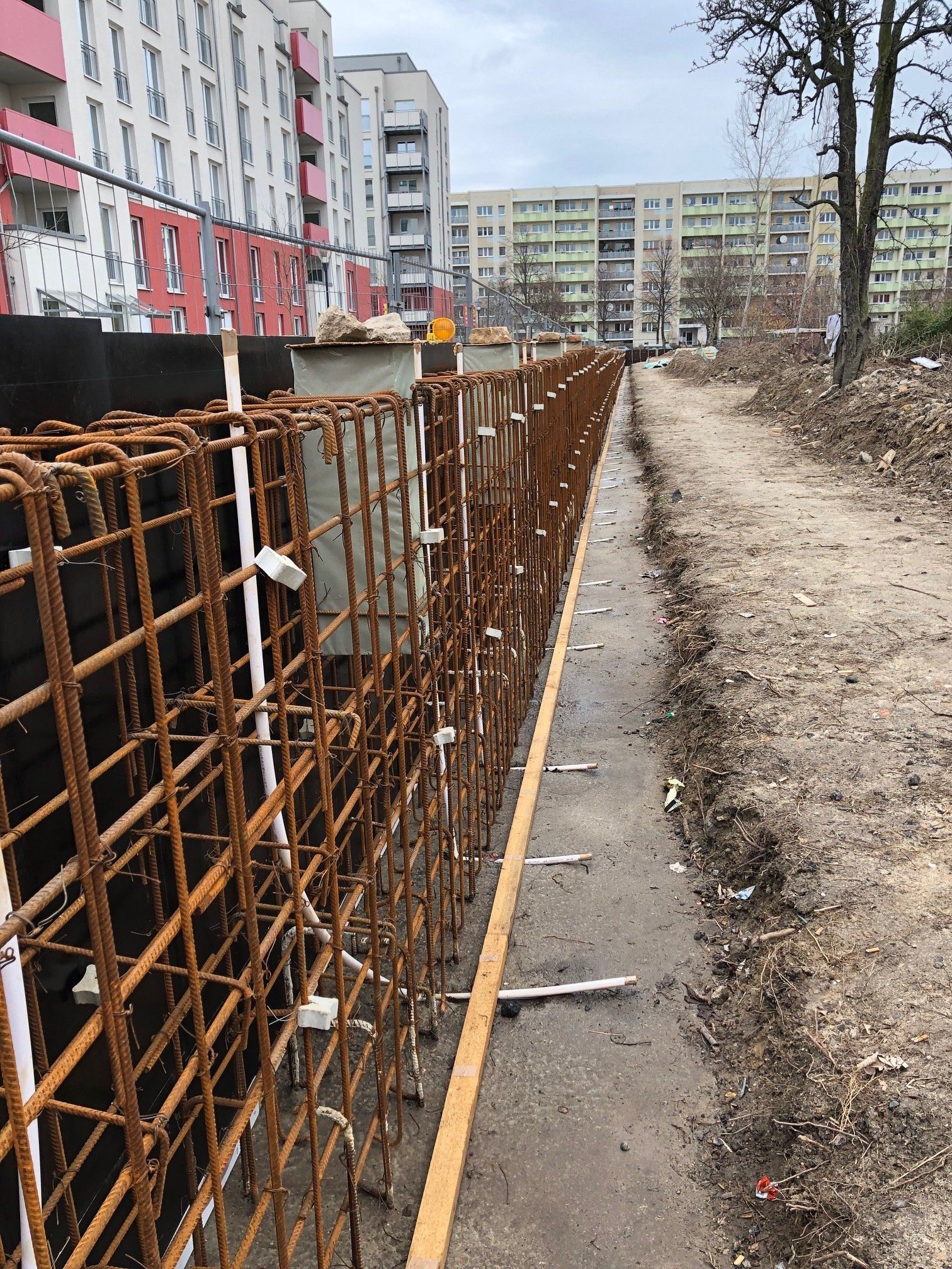 In einer Stadt wird ein Zaun gebaut , im Hintergrund sind viele Gebäude zu sehen.