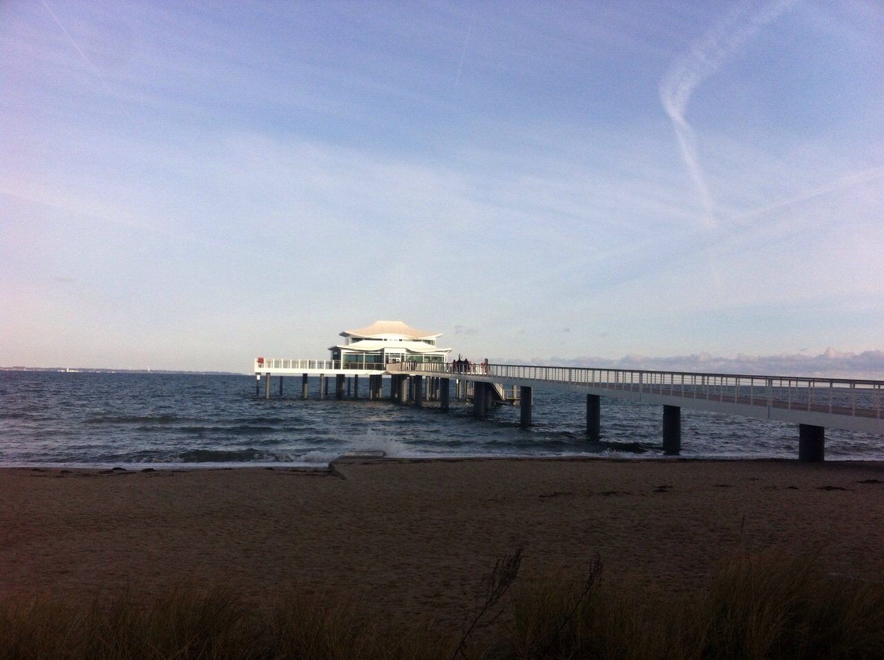 Ein Pier an einem Strand mit einem Gebäude im Hintergrund
