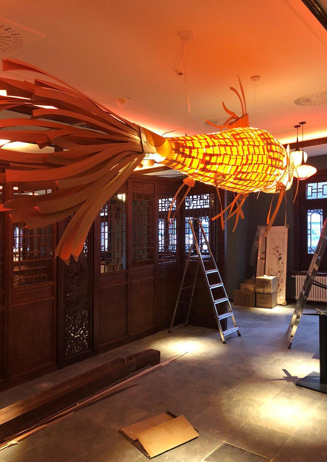 Eine große Vogelskulptur hängt von der Decke eines Raumes.
