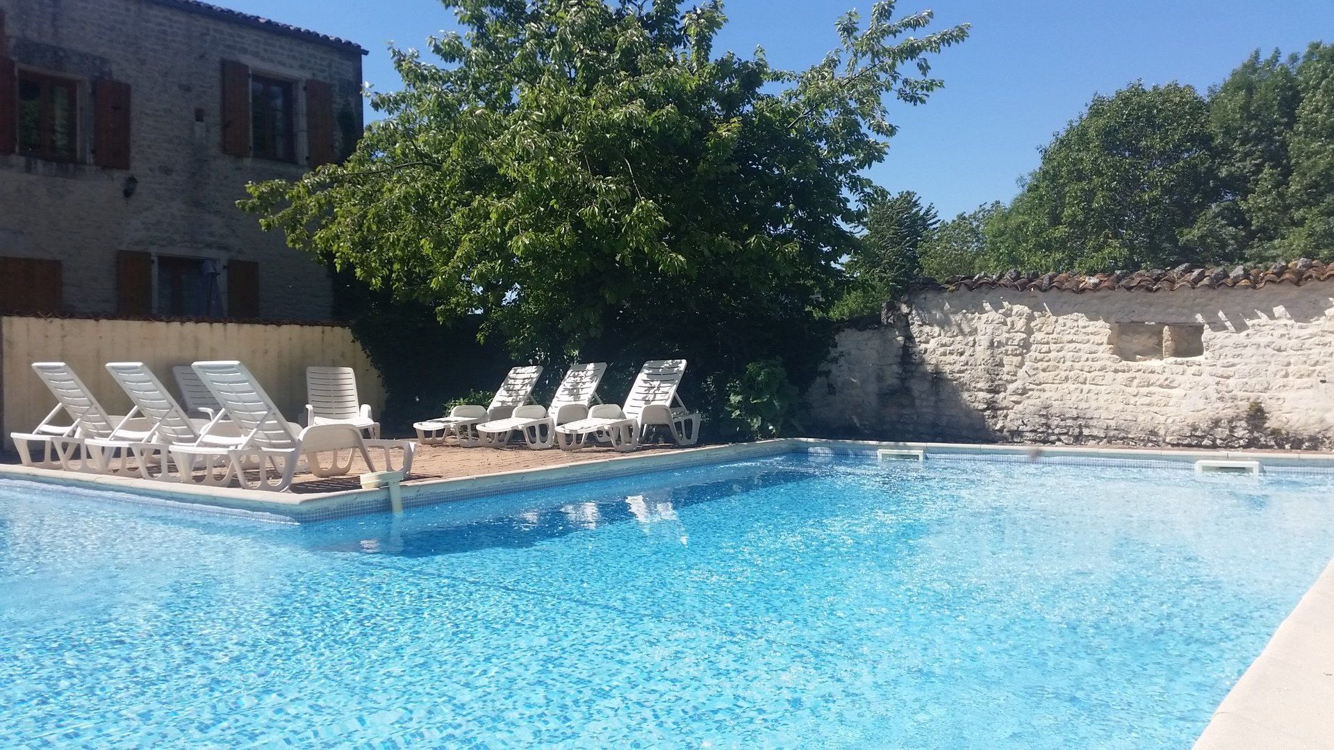 L shaped swimming pool with sunbeds on the surrounding terrace