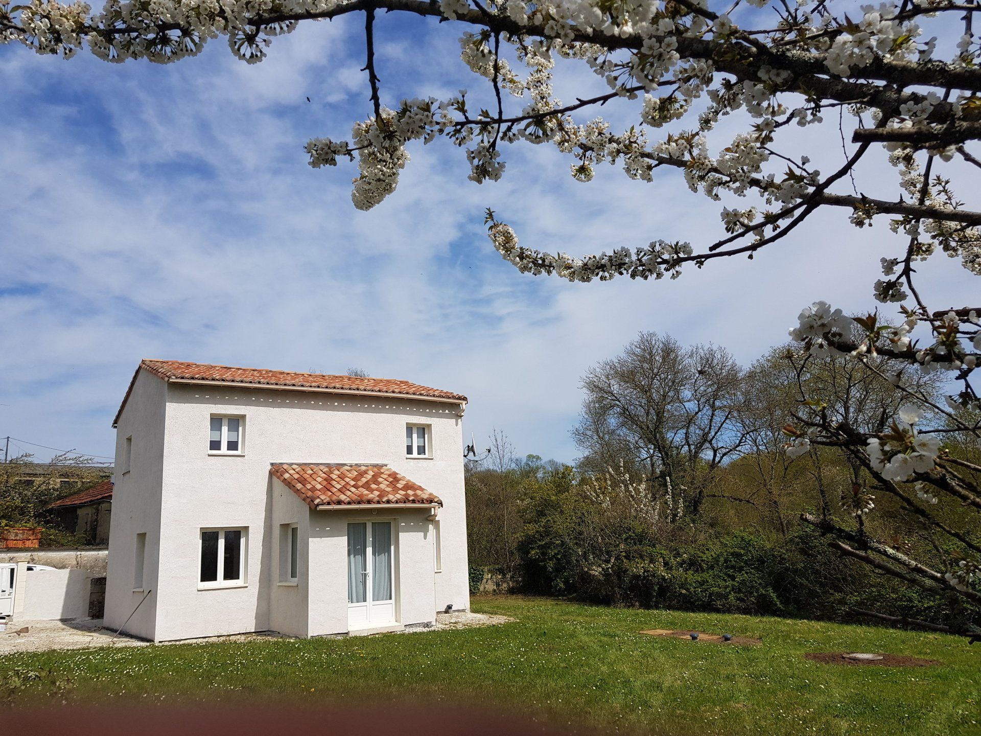 A two storey house painted white with red Roman canal tiled roof
