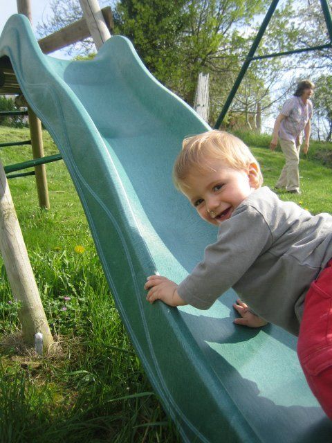 toddler smiling next to a green slide