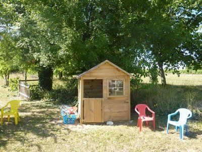 small childrens wooden cabin in a garden with small plastic chairs outside